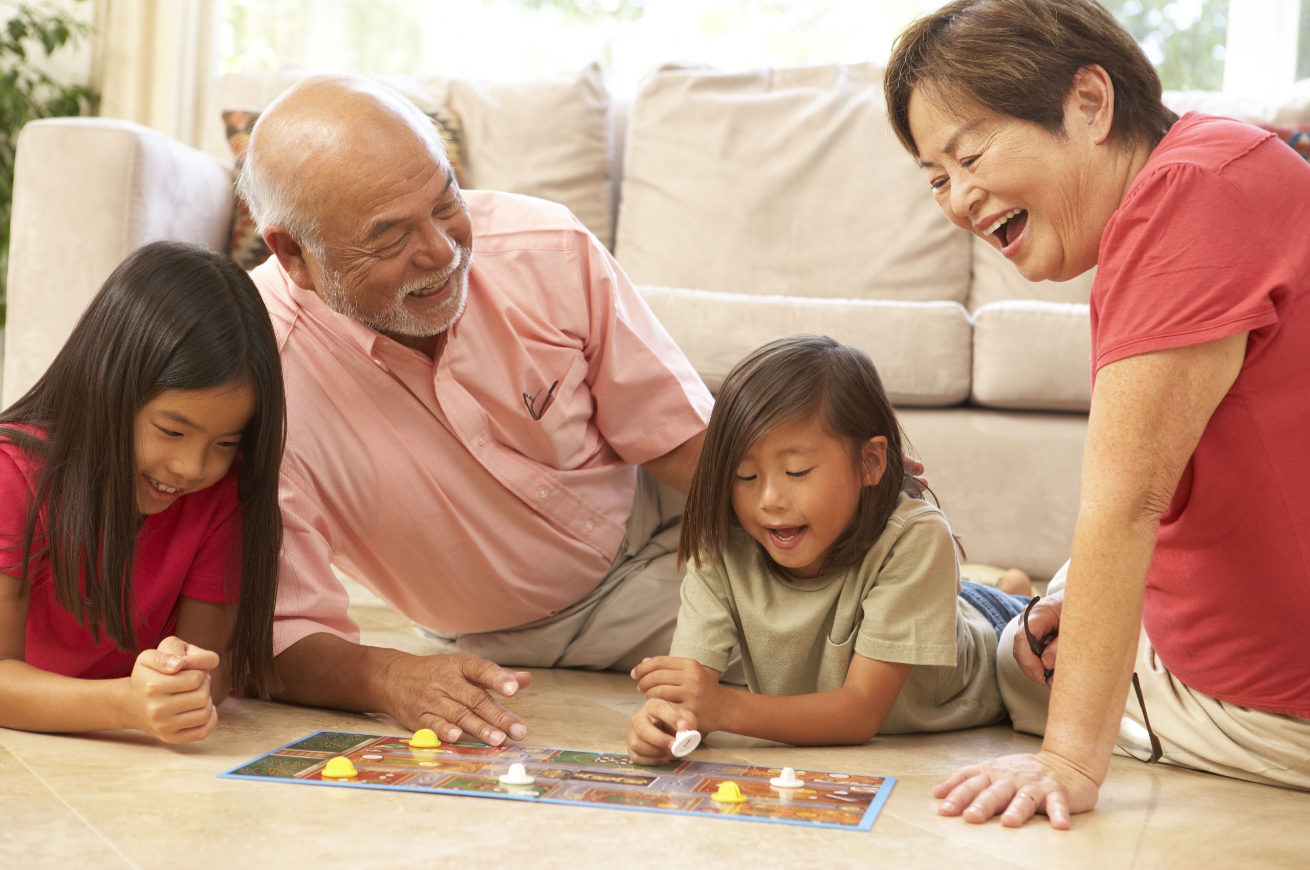 Happy grandparents playing board game with grandchildren