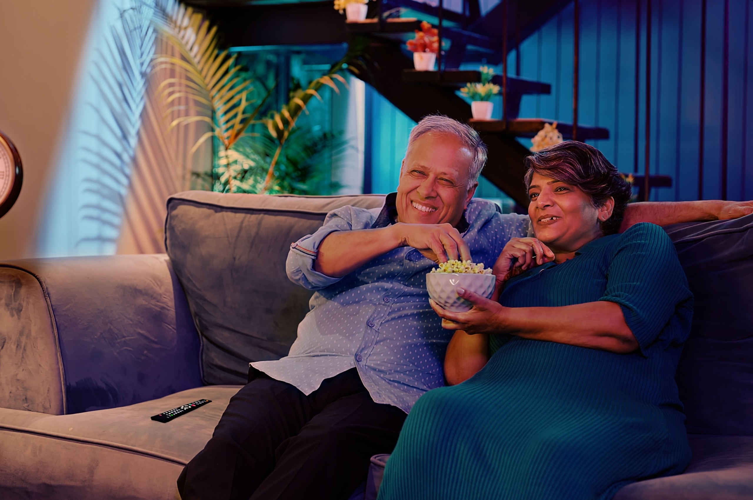 Happy retired couple watching a film on sofa